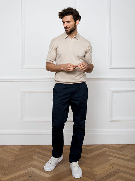Man wearing almond beige short sleeved polo sweater knit in 100% luxury and premium merino wool.